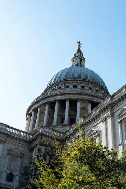 A narrow alleyway between two red-brick buildings leading to St. Paul's Cathedral with its large, domed roof and ornate architectural details visible in the background, set against an overcast sky. The image captures the urban environment typical of a city centre, highlighting the street’s tight space and the historic cathedral’s prominence, suitable for illustrating city relocation or house removal services near central London or similar urban settings, as provided by Man with Van St Pauls Cray.